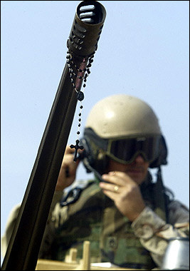 photo: a rosary hanging from an American machine gun barrel