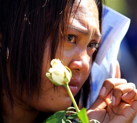 Pimchai Chudum holds a rose in memory of her brother during a tsunami commemoration ceremony in Khao Lak, Thailand