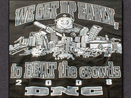 It's a black t-shirt with a cartoon of a giant policeman looming over the skyline of Denver, holding an oversized bat, with the caption "We get up early, to BEAT the crowds / 2008 DNC