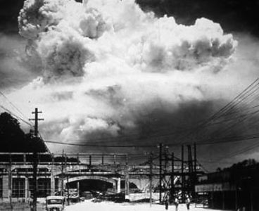 Here is a mushroom cloud, seen from the ground, towering into the sky over a bridge in Nagasaki.