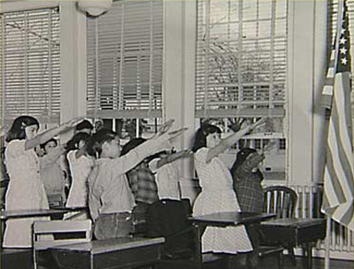 Here's a photograph of a group of white elementary school chidren, of about the same age, with their arms also raised--towards an American flag in the far right of the photograph.